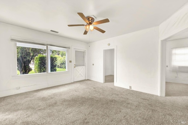 carpeted spare room featuring visible vents and ceiling fan