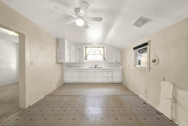 kitchen featuring visible vents, a ceiling fan, a sink, white cabinetry, and light floors