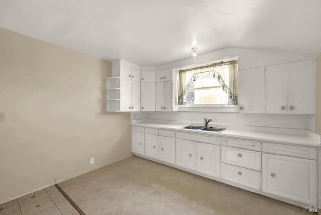 kitchen with a sink, lofted ceiling, and white cabinetry