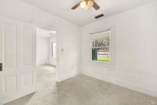 spare room featuring carpet flooring, plenty of natural light, visible vents, and a ceiling fan