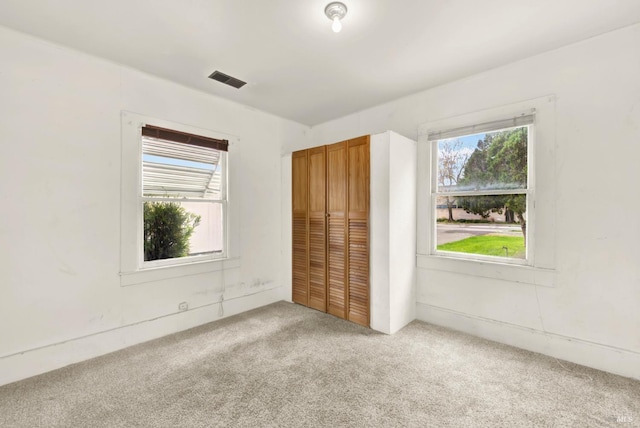 unfurnished bedroom with light colored carpet, visible vents, and a closet