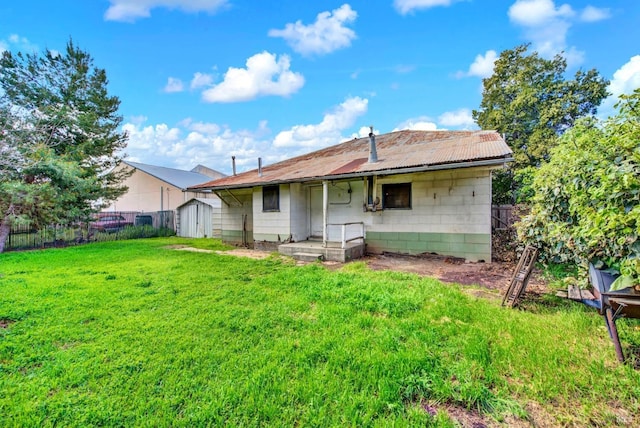 rear view of house featuring an outbuilding, a lawn, a fenced backyard, and a shed