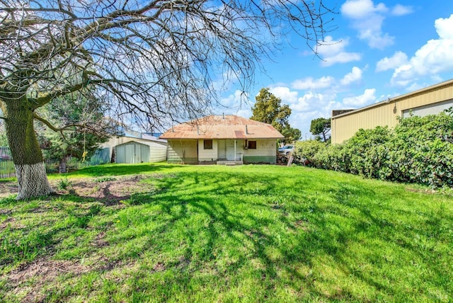 back of house with a storage unit, a lawn, and an outdoor structure