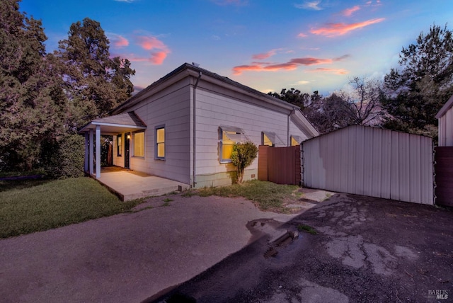 property exterior at dusk featuring a gate and a lawn