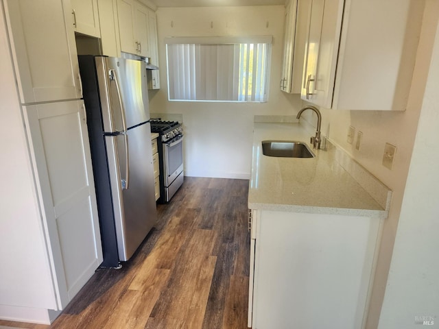 kitchen featuring a sink, light stone counters, white cabinetry, stainless steel appliances, and dark wood-style flooring