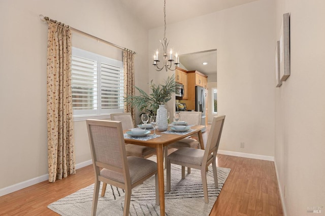 dining room with baseboards, a notable chandelier, and light wood-type flooring