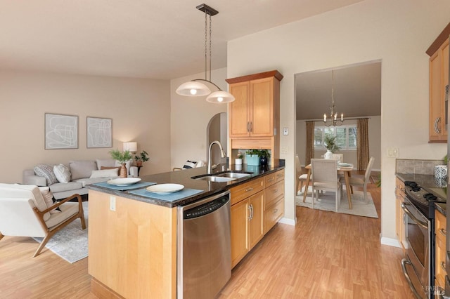 kitchen featuring stainless steel appliances, a sink, light wood-style floors, open floor plan, and a notable chandelier