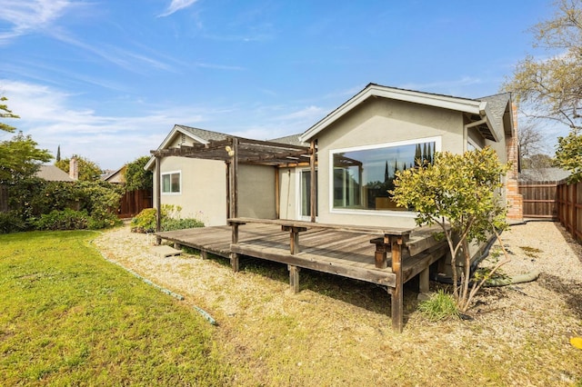 back of property featuring stucco siding, a yard, a deck, and a fenced backyard