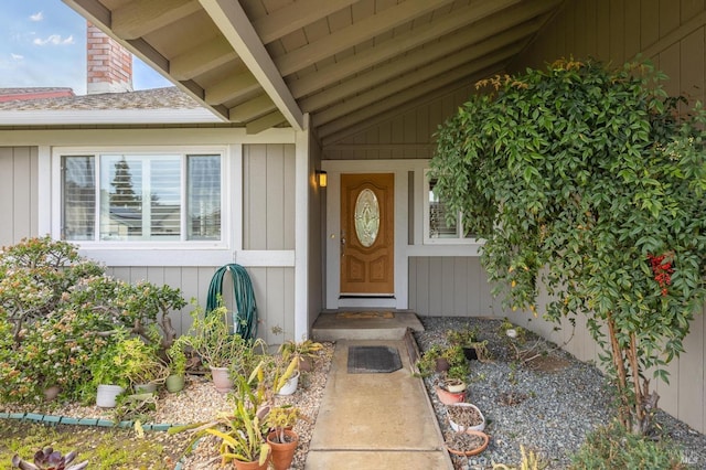entrance to property featuring board and batten siding, a shingled roof, and a chimney
