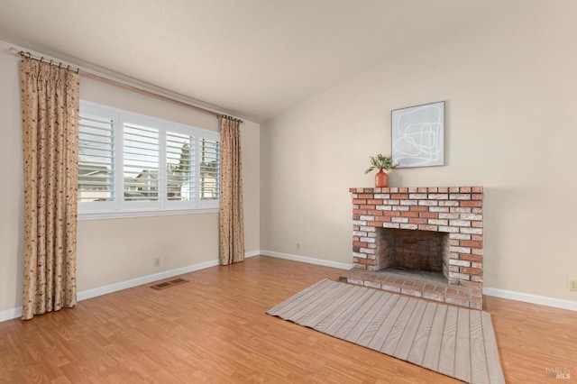 unfurnished living room with a fireplace, wood finished floors, lofted ceiling, and baseboards
