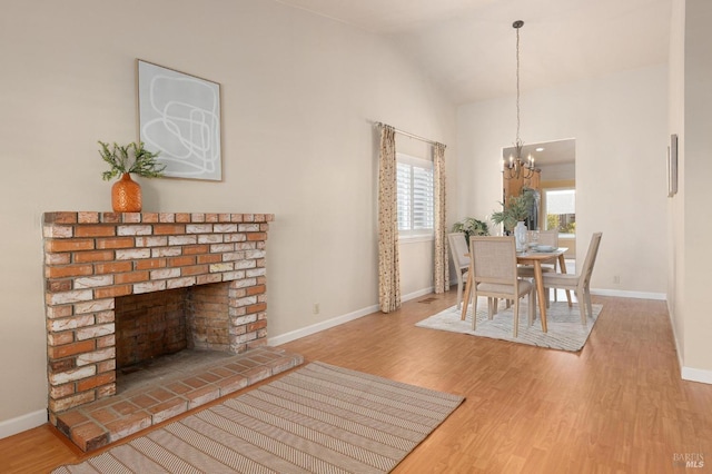 dining space with an inviting chandelier, lofted ceiling, wood finished floors, and baseboards