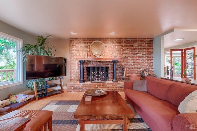 living area with a wealth of natural light, wood finished floors, and a fireplace