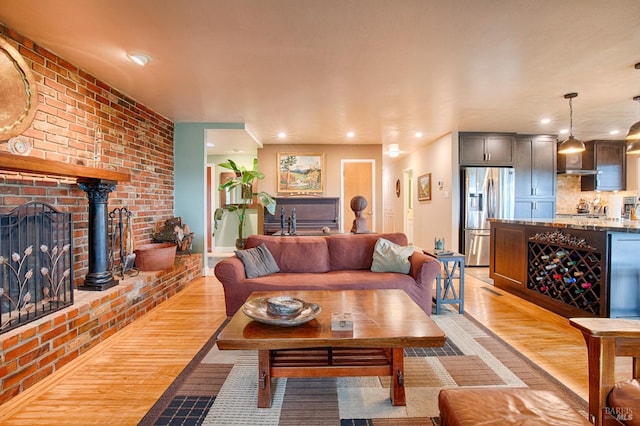 living area featuring a brick fireplace, light wood-style flooring, and recessed lighting