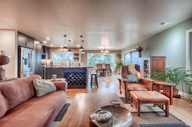 living area with baseboards, light wood-style floors, and an inviting chandelier