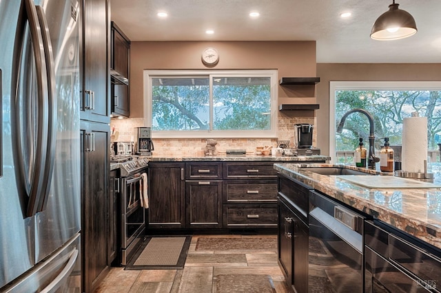 kitchen featuring tasteful backsplash, appliances with stainless steel finishes, light stone counters, and a sink