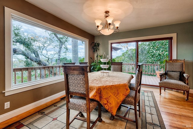 dining area featuring baseboards, light wood-type flooring, and a chandelier