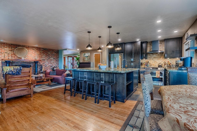 kitchen featuring light wood-style flooring, appliances with stainless steel finishes, wall chimney range hood, and open shelves