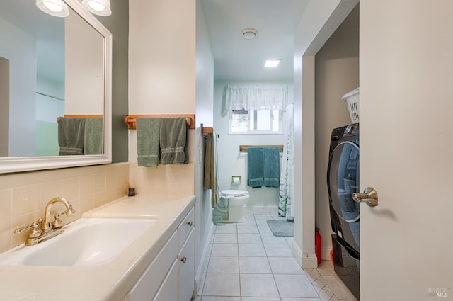 bathroom with backsplash, toilet, tile patterned floors, washer / clothes dryer, and vanity