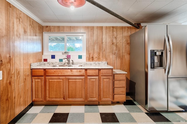 kitchen featuring brown cabinets, light floors, stainless steel fridge, and a sink