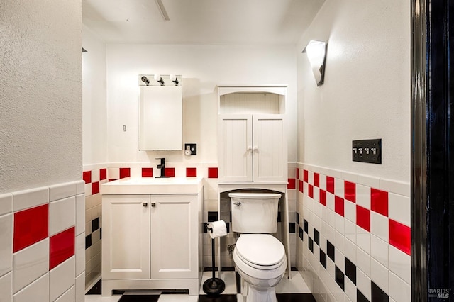 bathroom with vanity, tile walls, toilet, and a wainscoted wall