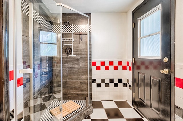 bathroom featuring a wealth of natural light, tile walls, wainscoting, and a shower stall