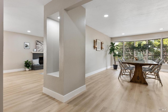 dining space with recessed lighting, baseboards, light wood-style floors, and a fireplace