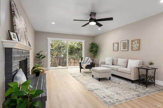 living room with a ceiling fan, wood finished floors, recessed lighting, baseboards, and a brick fireplace