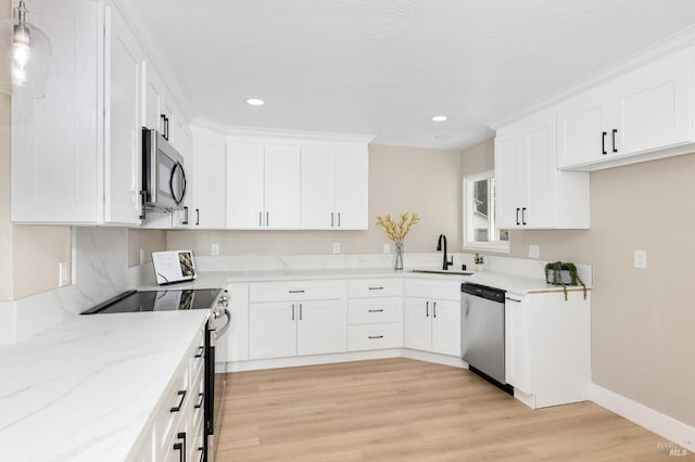 kitchen featuring a sink, light wood-type flooring, light stone counters, and appliances with stainless steel finishes