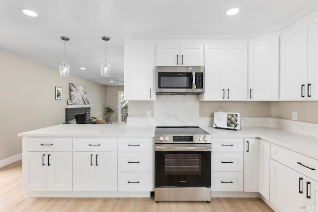 kitchen with light stone counters, appliances with stainless steel finishes, a peninsula, and white cabinets