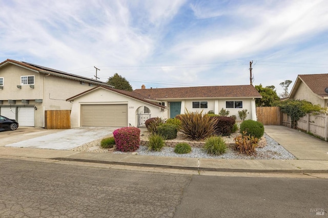 view of front of property featuring fence, a garage, driveway, and stucco siding