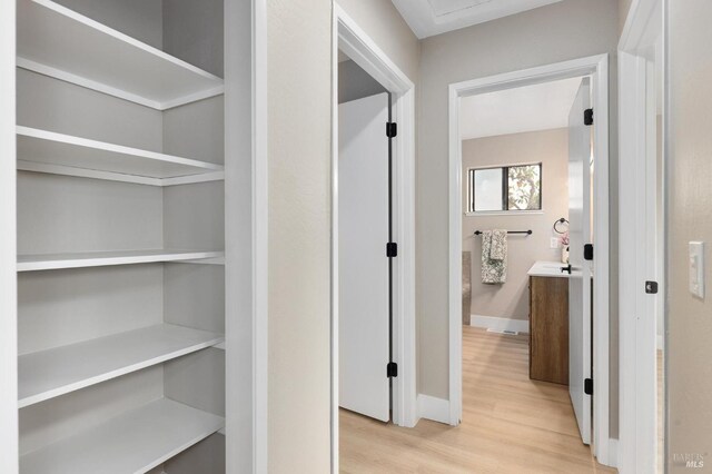 corridor featuring light wood-type flooring and baseboards