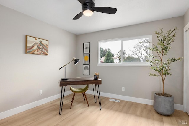 home office with visible vents, baseboards, light wood-style floors, and a ceiling fan