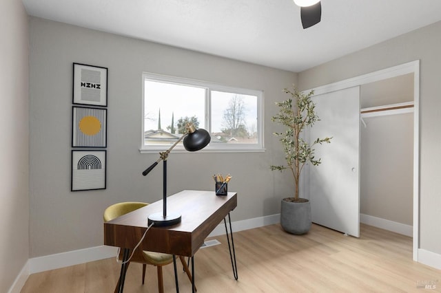 office featuring baseboards, light wood-style floors, and a ceiling fan