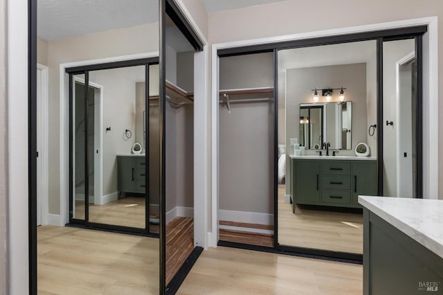 bathroom featuring baseboards, a spacious closet, wood finished floors, and vanity