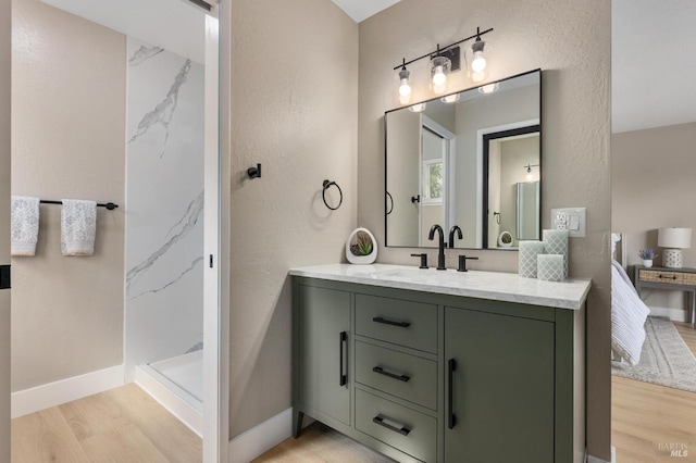 full bath with a shower stall, vanity, baseboards, and wood finished floors