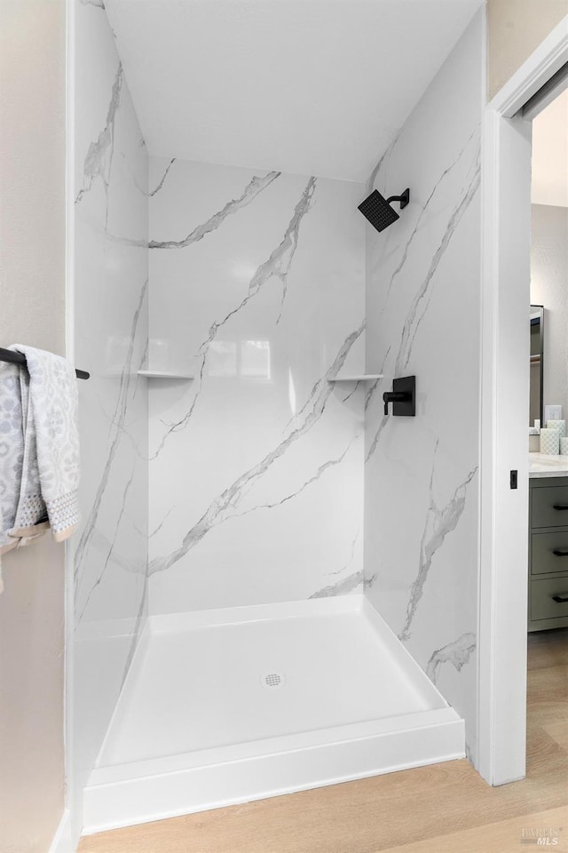 full bath featuring vanity, wood finished floors, and a marble finish shower