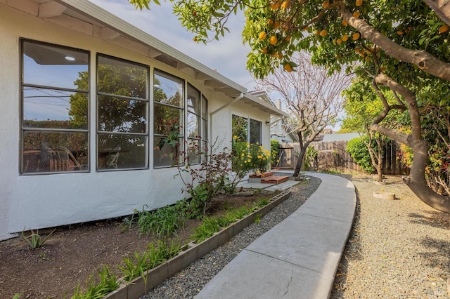 view of side of home featuring stucco siding and fence