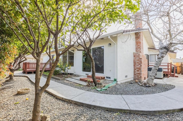 view of front facade featuring cooling unit, stucco siding, entry steps, crawl space, and a deck