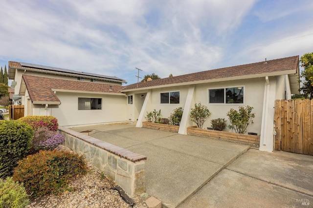 back of property featuring a patio area, fence, roof mounted solar panels, and stucco siding