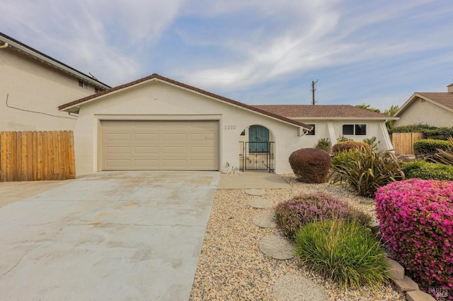 single story home with stucco siding, an attached garage, driveway, and fence