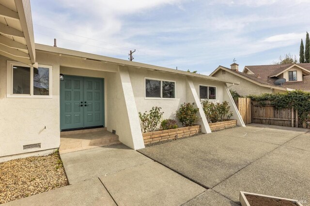 doorway to property with stucco siding and fence