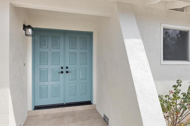 entrance to property with visible vents and stucco siding