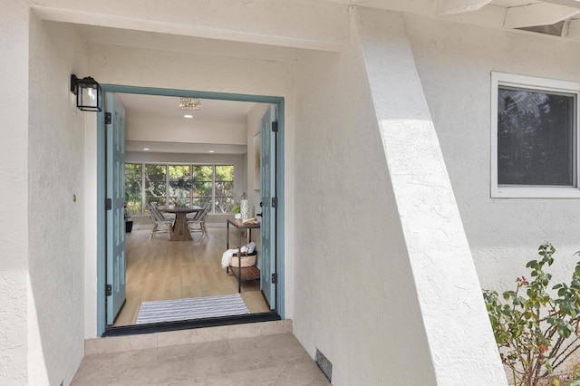 doorway to property featuring stucco siding and visible vents