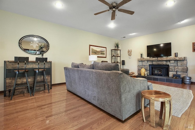 living area with baseboards, a fireplace, wood finished floors, and a ceiling fan