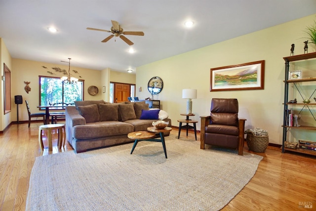 living room with recessed lighting, ceiling fan with notable chandelier, baseboards, and light wood finished floors