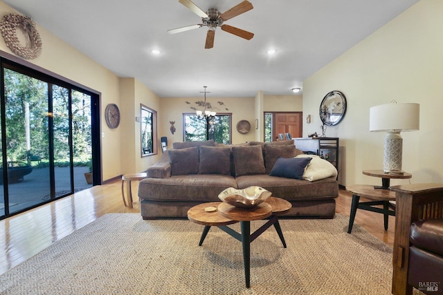 living room with recessed lighting, ceiling fan with notable chandelier, baseboards, and light wood-style floors