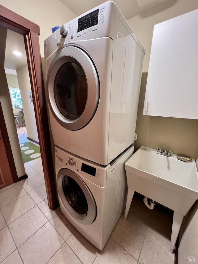 laundry room featuring stacked washer and clothes dryer, light tile patterned flooring, and laundry area