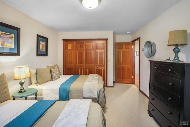 bedroom featuring a closet, light carpet, and baseboards