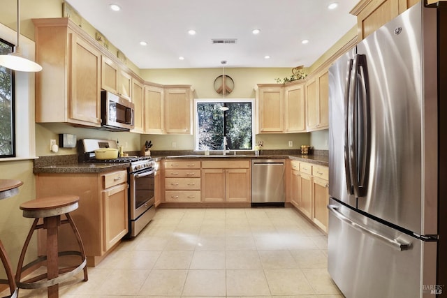 kitchen with dark countertops, light brown cabinets, visible vents, and appliances with stainless steel finishes