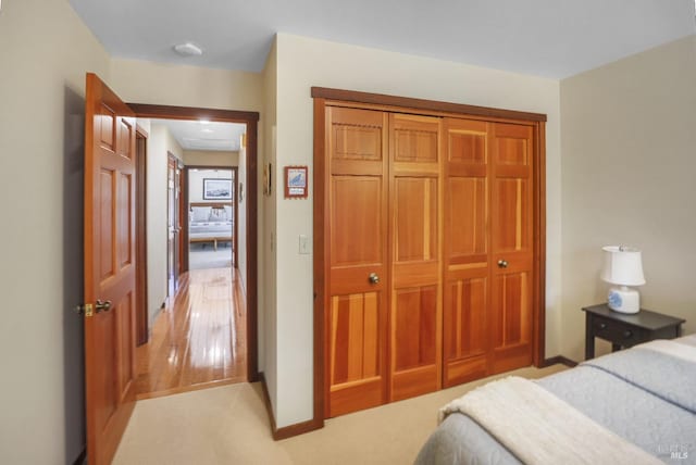 bedroom with a closet, baseboards, and light carpet